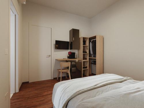 a bedroom with a bed and a desk and a kitchen at Marysel Rooms in Olbia