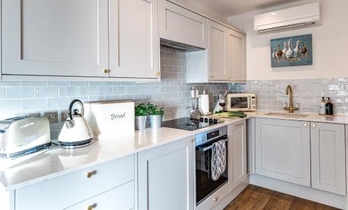 a white kitchen with white cabinets and appliances at Honey Pot, Chipping Campden, parking, garden, late check-out in Chipping Campden