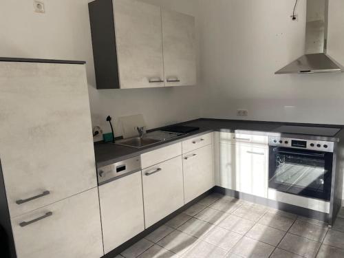 a kitchen with white cabinets and a sink and a stove at Gemütlicher Raum mit eigenem Bad in Gönnern