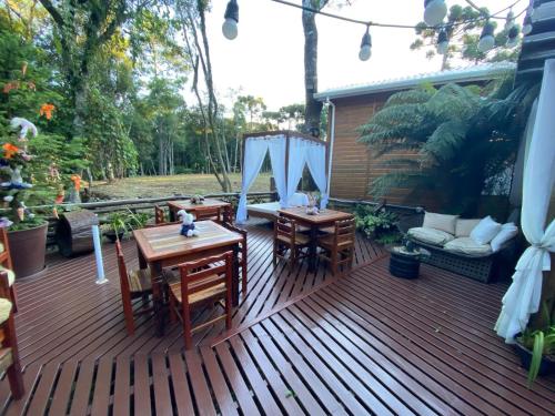 a wooden deck with two tables and a couch at Chales e Spa Exclusive - Localizado Proximo do Centro in Canela