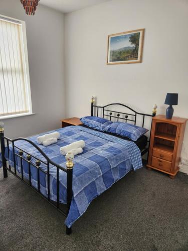 a bedroom with a blue bed with two towels on it at House in Newton-le-Willows in Newton-le-Willows