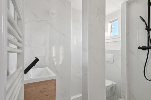 ein weißes Bad mit einer Dusche und einem Waschbecken in der Unterkunft Charmant T2 - Coeur d'Arpajon in Arpajon