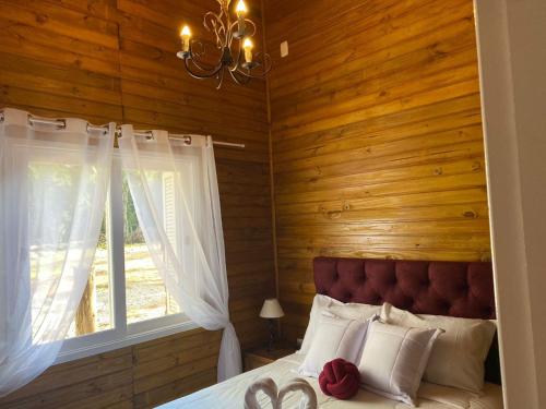 a bedroom with a bed with wooden walls and a window at Chales e Spa Exclusive - Localizado Proximo do Centro in Canela