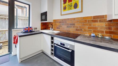 a kitchen with a sink and a brick wall at Pitts Cottage Annexe in Bladon
