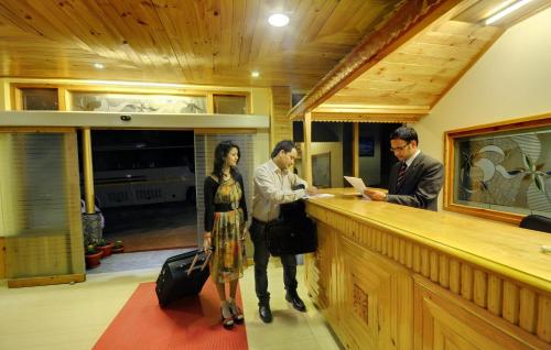 a group of three people standing at a bar at The Holiday Resorts and Cottages in Manāli