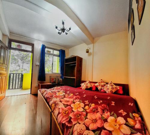 um quarto com uma cama com uma colcha vermelha com flores em Silver Sun Official em Darjeeling