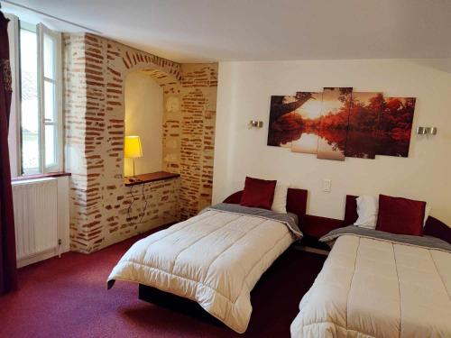 a bedroom with two beds and a brick wall at Hôtel Jean XXII in Cahors