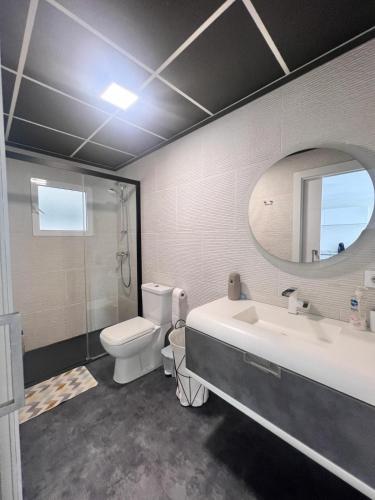 bagno con lavandino, servizi igienici e specchio di Casa Mayra a Los Caparroses