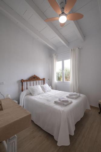 a white bedroom with a bed and a ceiling fan at KASSIOPEA in Cala Blanca