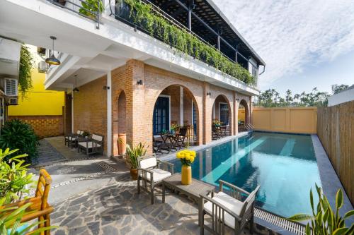 an outdoor swimming pool with chairs and a building at Calm House 3 in Hoi An