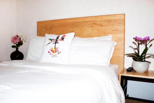 a bedroom with a white bed with a wooden headboard at Hospedaje Donaji in Oaxaca City