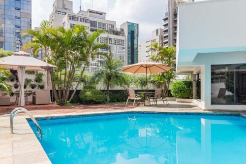 una piscina con sillas, sombrilla y edificios en FORTUNE RESIDENCE JARDINS - FLAT275 - Próximo da Avenida Paulista, en São Paulo