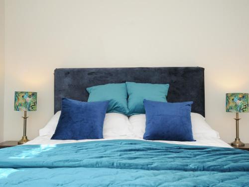 a bed with blue and white sheets and pillows at The Bower in Helston