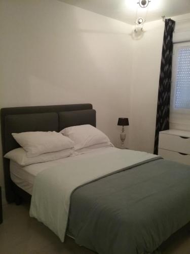 1 dormitorio con 1 cama con sábanas y almohadas blancas en Appart'hôtel en Beauvais
