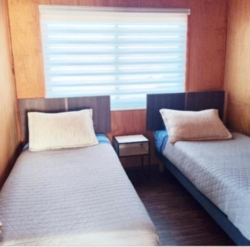 two beds in a small room with a window at San José Hotel Boutique & Spa in La Ligua