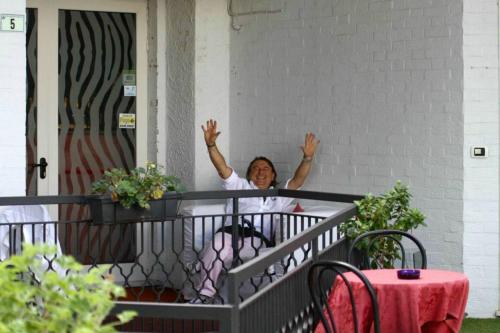 a woman sitting on a balcony with her hands in the air at Locanda San Biagio in Misano Adriatico