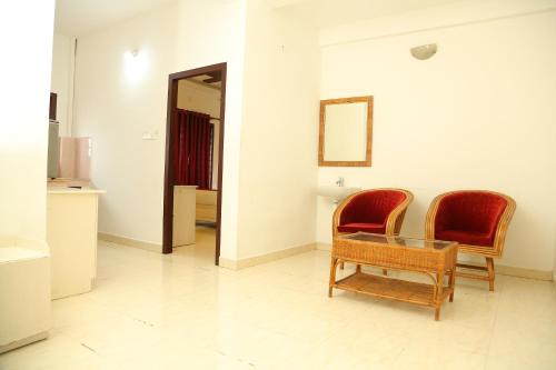 a living room with two chairs and a glass table at Ritzy Village Residency in Cochin