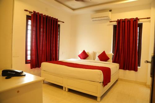 1 dormitorio con 1 cama grande y cortinas rojas en Ritzy Village Residency, en Kochi