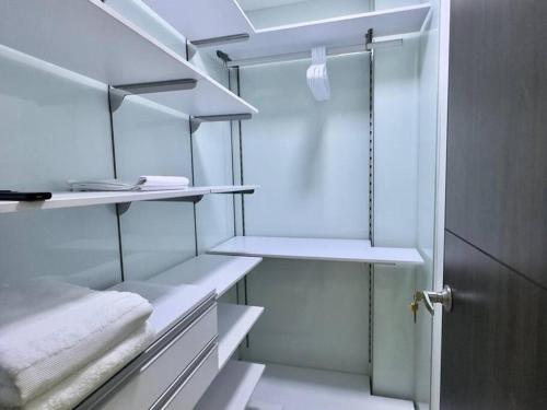 einen begehbaren Kleiderschrank mit weißen Regalen und einer Tür in der Unterkunft 1301 Luxury Penthouse, Poblado in Medellín