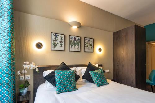 a bedroom with a white bed with blue pillows at Garlande Hôtel Avignon Centre in Avignon