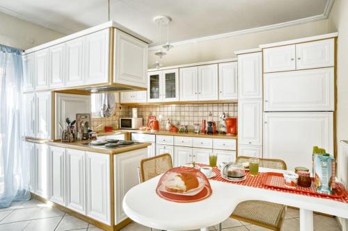 a kitchen with white cabinets and a table with a cake on it at Evita's ikia seaside luxury house in Mesongi