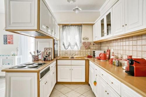a kitchen with white cabinets and a stove top oven at Evita's ikia seaside luxury house in Mesongi