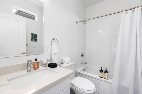 a white bathroom with a toilet and a sink at Martell's Sunspear Sweet Suite in Seattle