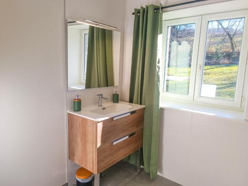 een badkamer met een wastafel, een spiegel en een raam bij Le gîte d'Ouillon in Saint-Hostien