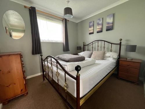 a bedroom with a bed with white sheets and a window at 26, Two bed chalet on Bermuda holiday park, Hemsby - Sleeps 5, bed linen and towels included - with onsite entertainment and more options close by in Great Yarmouth