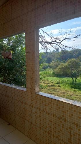 a window in a bathroom with a view of a field at Alugo casa no vale do capao in Palmeiras