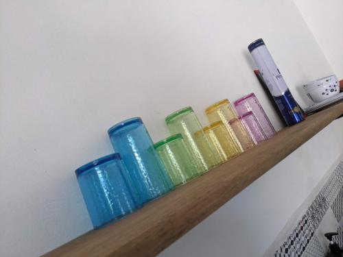 a shelf with different colored glass vases on it at Casa Foto Estudios in El Cuyo