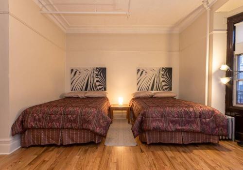 two beds in a room with wooden floors at Comfortable One Bedroom Apartment in New York