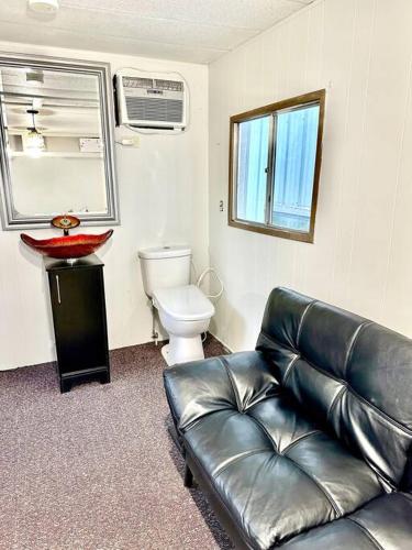 a living room with a leather couch and a toilet at Trestle Creeks Farmhouse Fort Tiny House in Bloomington