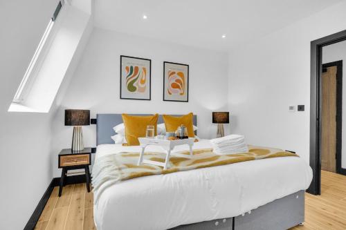 a bedroom with a large white bed with yellow pillows at homely- North London Penthouse Apartment Finchley in Finchley