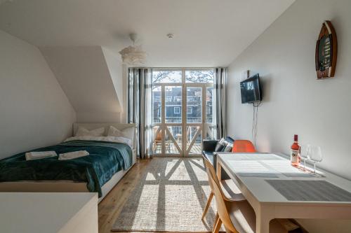 1 dormitorio con cama, escritorio y mesa en SOLEMAR romantic studio with lagoon View!, en Pervalka