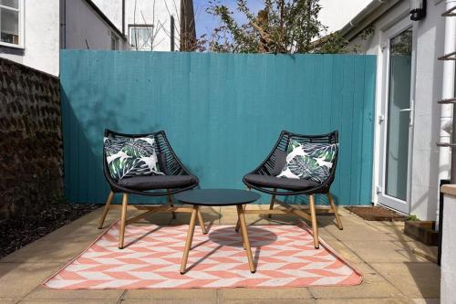 three chairs and a table in front of a blue wall at The Lorelei Chic Urban Retreat with Terrace in Brighton in Brighton & Hove