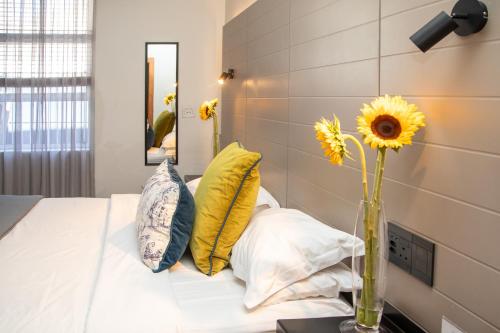 a bedroom with a bed with yellow pillows and a vase with flowers at Loddey`s Guest House - by Beach Collection in Strand