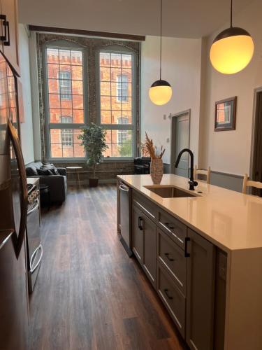 a kitchen with a sink and a living room at Prime 2BR Condo Historic Morris Ave, Downtown Birmingham in Birmingham