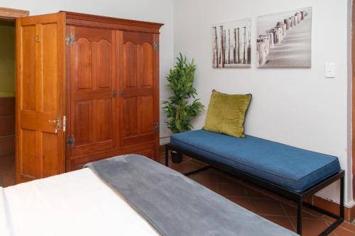 a bedroom with a bed and a chair and a cabinet at Loddey`s Guest House - by Beach Collection in Strand
