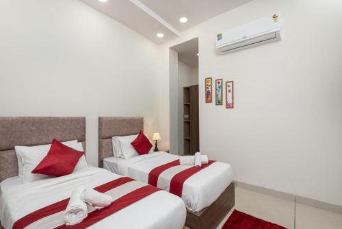 two beds in a hotel room with red pillows at The Setu Hotel & Resorts in Faridabad