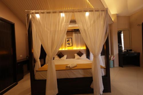 Lavender Heights في لونافالا: غرفة نوم مع سرير مظلة مع ستائر بيضاء
