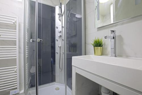 a white bathroom with a shower and a sink at Equerre - Balcony studio near Buttes Chaumont in Paris