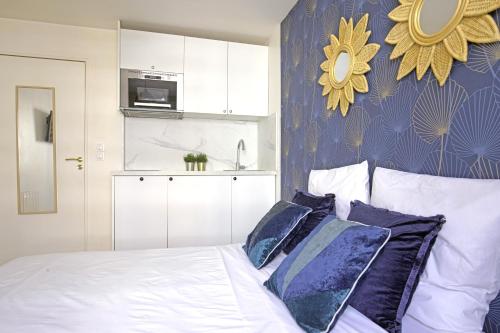 une chambre avec un lit avec des oreillers bleus et blancs dans l'établissement Balcony studio near Buttes Chaumont, à Paris