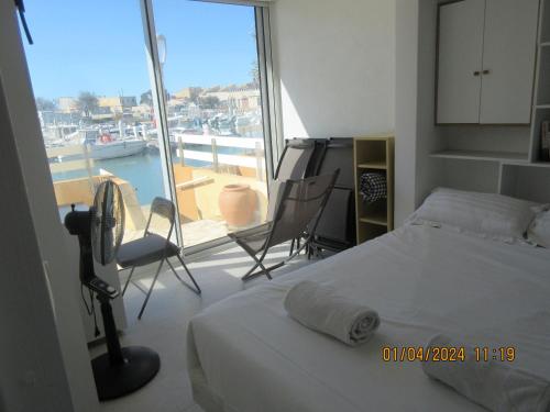a bedroom with a bed and a balcony with a boat at idéal touristes in Frontignan