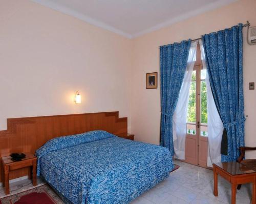 a bedroom with a blue bed and a window at Hotel Splendid in Fès