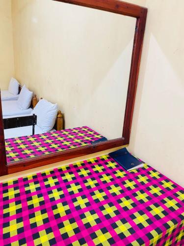 a bed in a room with a mirror on it at YMCA Guest house in Batticaloa