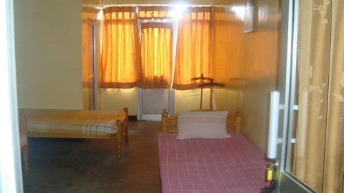 YMCA Guest house في باتيكالوا: غرفة بسريرين وستائر صفراء