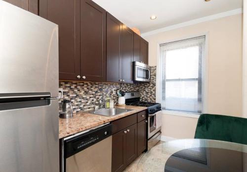 uma cozinha com armários castanhos e um frigorífico de aço inoxidável em Spacious 1BR Apartment em Nova York