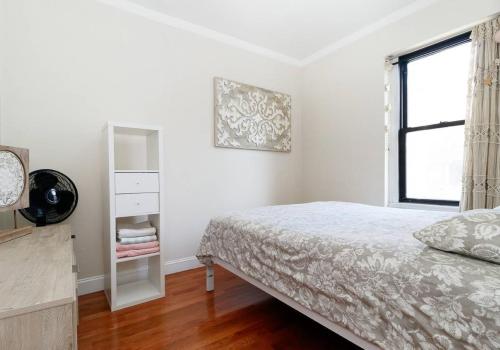 um quarto branco com uma cama e uma janela em Spacious 1BR Apartment em Nova York
