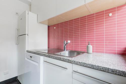 uma cozinha com um lavatório e uma parede em azulejos cor-de-rosa em Castle Palm View em Leiria